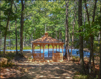 12 x 12 Cedar Rectangular Gazebo shown with red cedar deck, 1x3 standard railings, straight posts, straight fascia, cedar shake shingles, unstained, stainless steel hardware, additional entrance, 8 bench sections and cupola. 