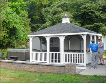 14 x 14 Vinyl Rectangular Gazebo shown with Harbor Grey composite deck, 1x1 stated railings, straight posts, standard braces, no top railing, straight fascia, 4 track window system with screens, Rustic Black asphalt shingles, oil rubbed bronze Avruc outdoor ceiling fan, stainless steel hardware, screened floor, Hidden Wiring w/ 1 Receptacle & Switch, 3 additional receptacle. 