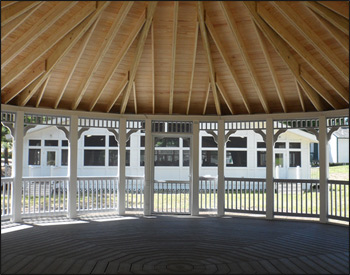 Interior of 30 Vinyl Dodecagon Gazebo shown with Gray composite deck, 1x1 railings, standard braces, no cupola, full set of screens and screen door, Old English Pewter asphalt shingles, Appliance White Avruc Outdoor Ceiling Fan w/ Light, screened floor, Hidden Wiring w/ 1 Receptacle & Switch, extra receptacle, additional door, straight posts, and top railing sections.